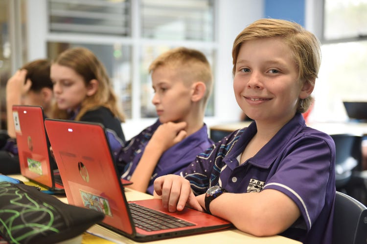 Three students at their desk using their laptops.